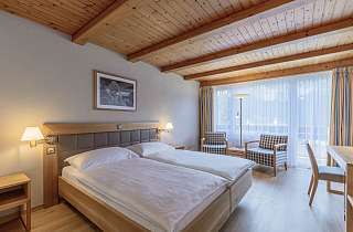 Doppelzimmer Standard im Sunstar Hotel Grindelwald mit Holztäfer-Decke, Sitzecke am Fenster und Schreibtisch
