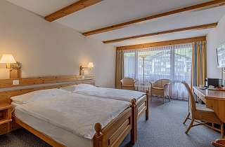 Doppelzimmer Standard im Sunstar Hotel Grindelwald mit Holzbett, Sitzecke am Fenster und Schreibtisch