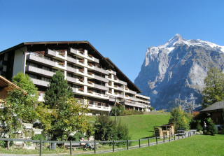 Aussenansicht des Sunstar Hotels in Grindelwald mit Blick auf die imposante Berglandschaft und grüne Wiesen