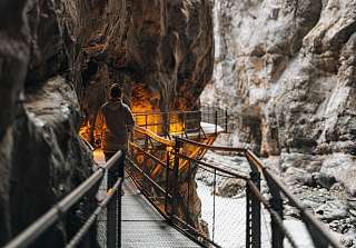 Person geht über einen Steg durch die enge, beleuchtete Gletscherschlucht in Grindelwald