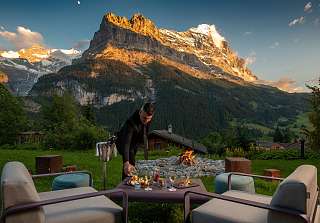 Cozy lounge terrace with fire pit overlooking the mountain landscape of Grindelwald at sunset