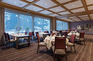 Eingedeckte Tische im Restaurant des Sunstar Hotels Grindelwald mit Panoramafenstern und Blick auf verschneite Berge