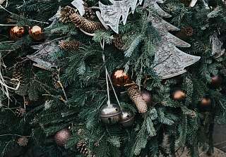 Fir branches with pine cones, shiny copper baubles, two silver bells and tree shapes made of birch bark. Photo: Alisa Anton / Unsplash