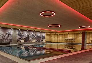 Innenpool im Spa des Sunstar Hotels Grindelwald mit runden Lichtelementen an der Decke und Bergpanorama-Wandbild