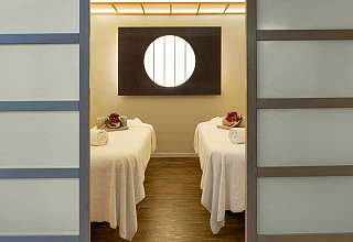 Behandlungsraum im Spa des Sunstar Hotels Grindelwald mit zwei Massageliegen und rundem Lichtelement an der Wand