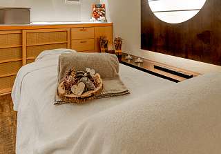 Massage bed with natural decoration in a warmly lit wellness room with a round wall feature at Sunstar Grindelwald