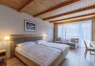 Chambre double Standard Eiger avec lit, coin salon et accès au balcon en plein jour