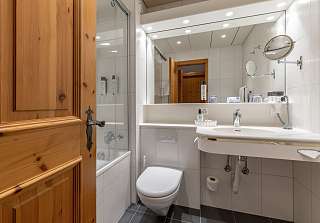 Salle de bains dans la chambre double Standard avec baignoire, lavabo et porte en bois