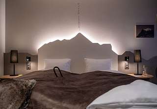 Chambre double Wetterhorn avec lit, bureau et coin salon confortable en soirée