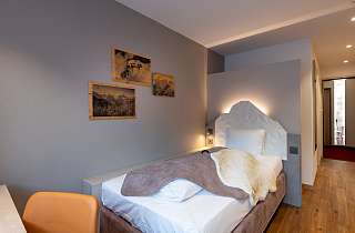 Einzelzimmer Budget Nova im Sunstar Hotel Grindelwald mit beleuchtetem Kopfteil und gerahmten Bildern an der Wand