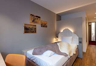 Einzelzimmer Budget Nova im Sunstar Hotel Grindelwald mit beleuchtetem Kopfteil und gerahmten Bildern an der Wand