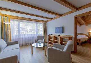 Espace salon de la Chambre familiale Village au Sunstar Grindelwald avec coin salon et vue sur le village