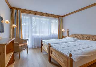 Espace nuit de la Chambre familiale Eiger au Sunstar Grindelwald avec lit double et accès au balcon