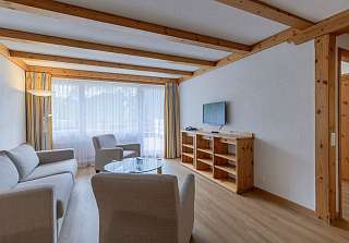 Espace salon de la Chambre familiale Eiger au Sunstar Grindelwald avec coin salon et télévision