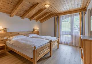 Chambre à coucher de la Suite First au Sunstar Grindelwald avec lit double sous un plafond à poutres en bois