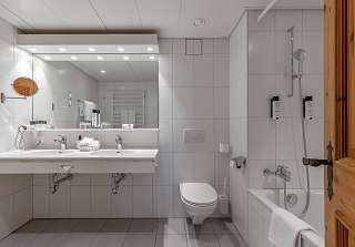 Salle de bains de la Suite First au Sunstar Grindelwald avec double vasque et baignoire