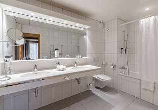 Salle de bains de la Suite Junior au Sunstar Grindelwald avec double vasque et baignoire