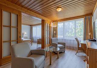 Espace salon de la Suite Junior au Sunstar Grindelwald avec coin salon et vue sur la chambre