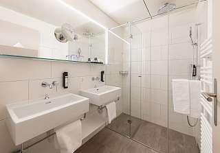 Salle de bains de la Suite Mettenberg au Sunstar Grindelwald avec double vasque et douche à effet pluie