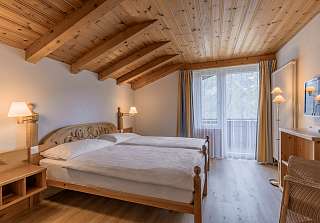 Espace nuit de la Suite Wetterhorn au Sunstar Grindelwald avec lit double sous un plafond à poutres en bois